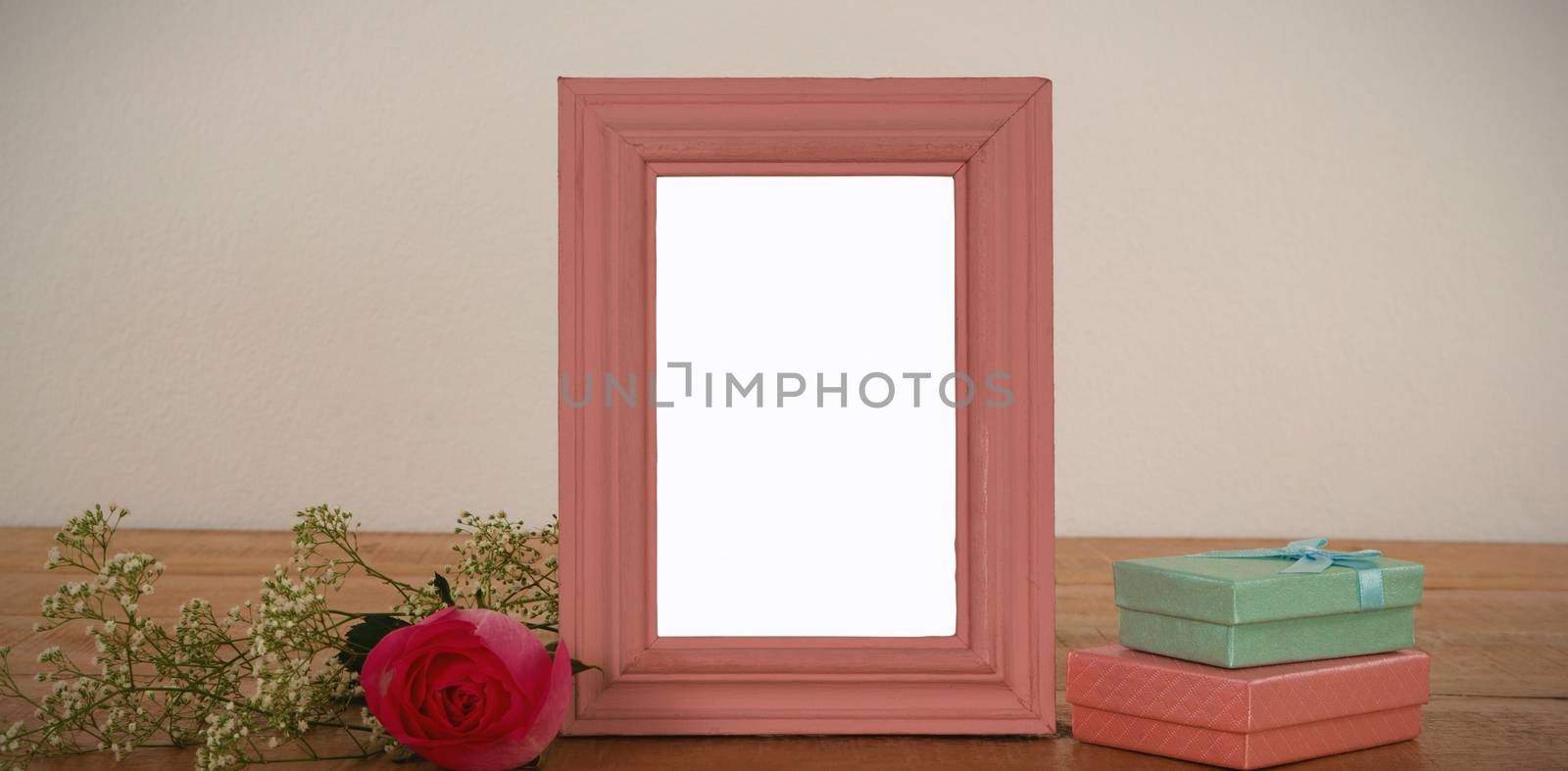 Empty photo frame, rose flower and gift boxes on a table