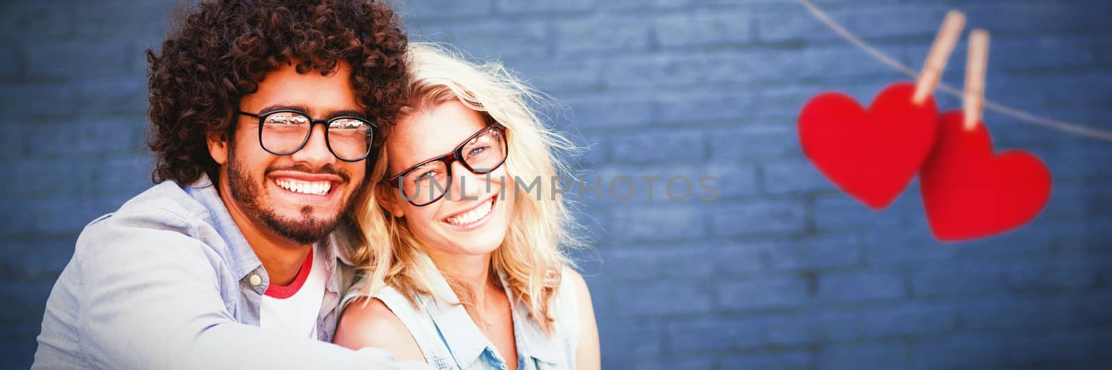 Hearts hanging on a line against portrait of young couple in spectacles