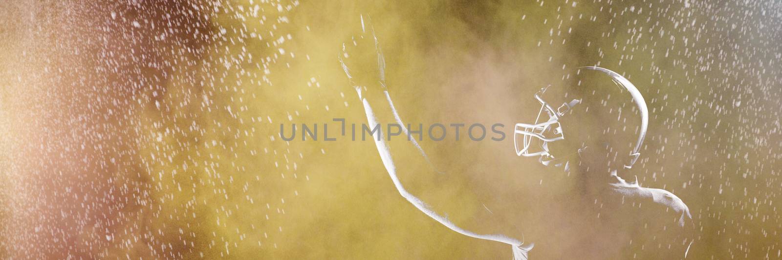 Splashing of dust powder against american football player in helmet pointing upwards