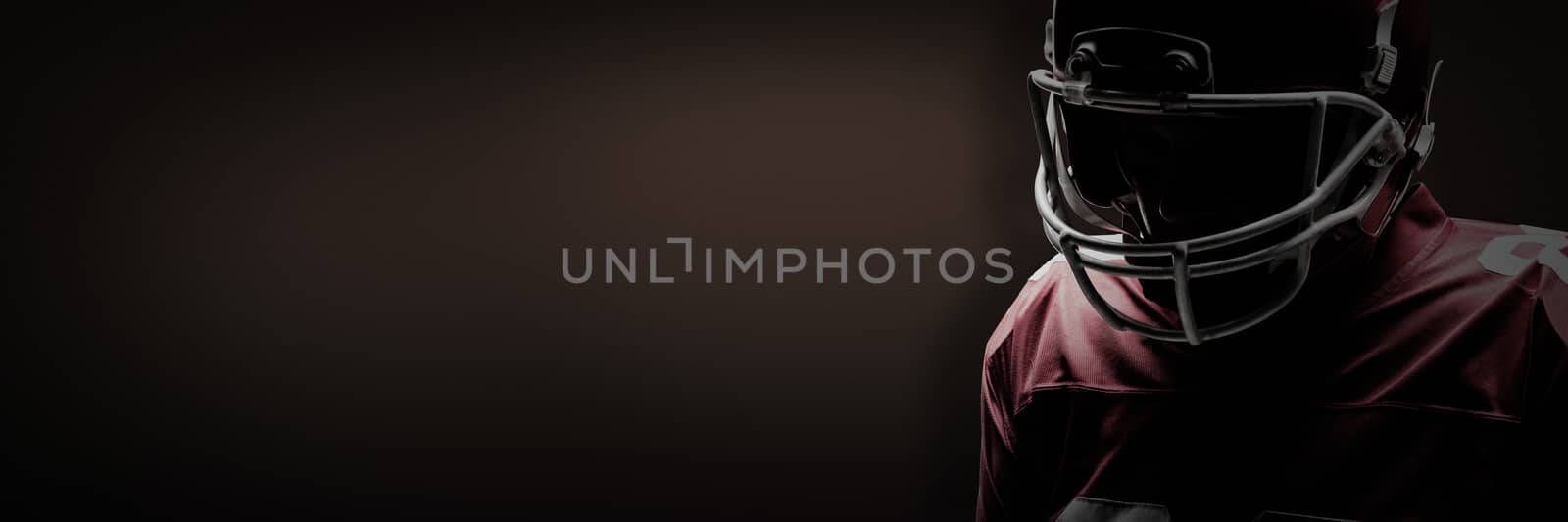 American football player standing in rugby helmet against dark brown background