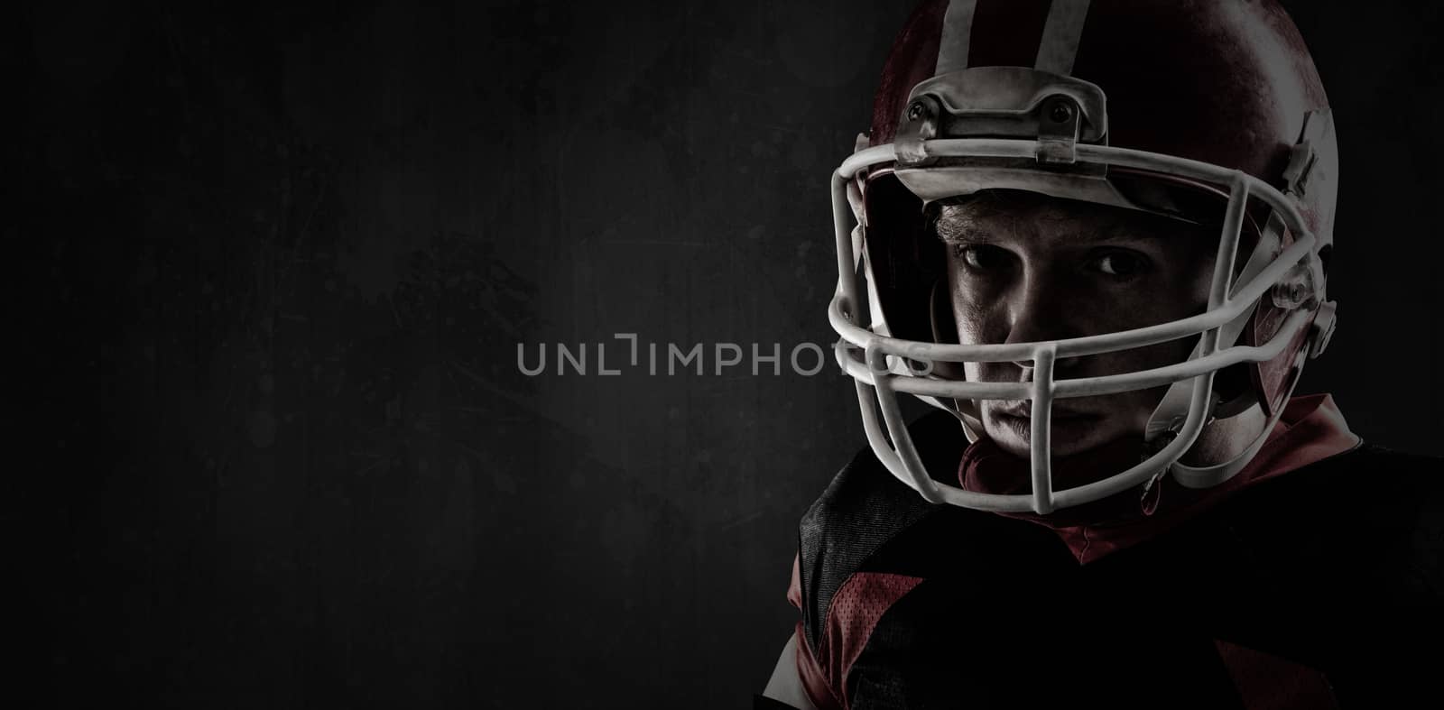 American football player standing with rugby helmet against full frame shot of grunged concrete wall