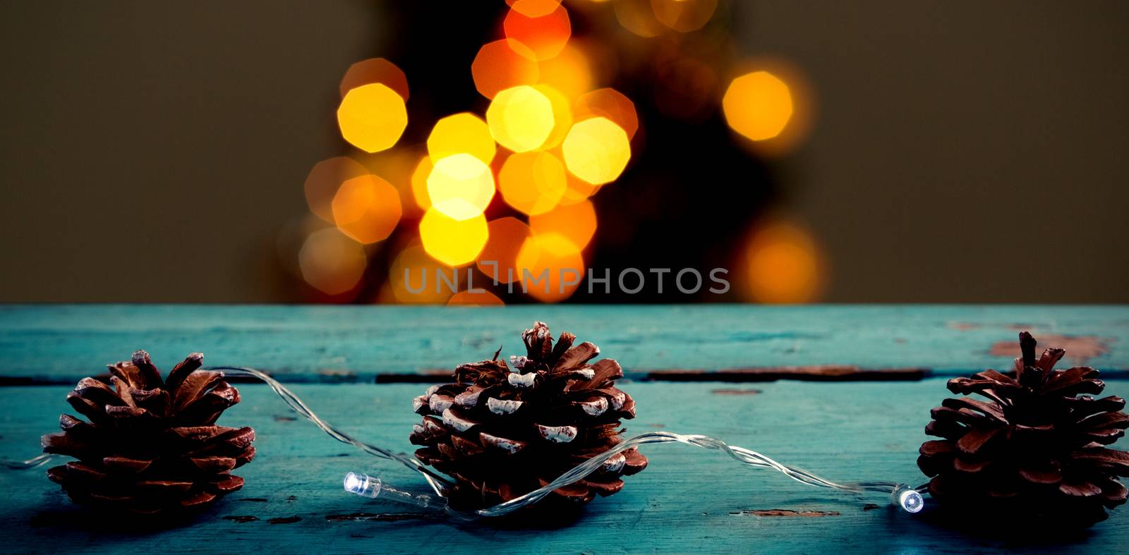 Pine cones decorated with christmas light against copy space with gift and snow