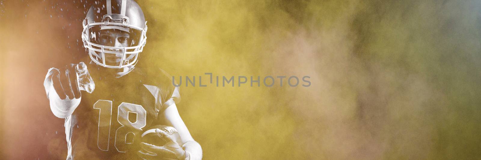 Splashing of dust powder against american football player in helmet holding rugby ball and pointing