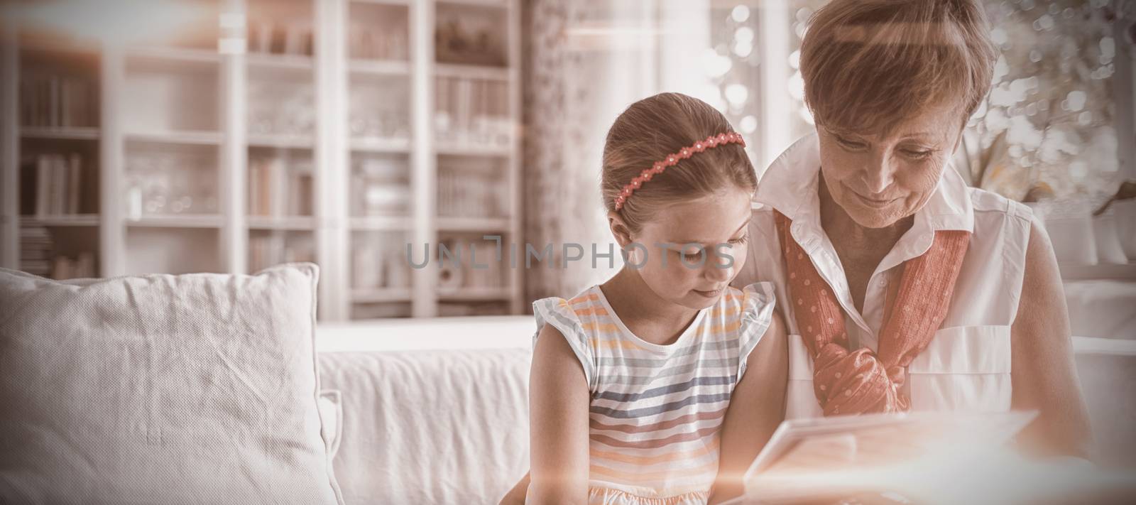 Senior woman and her granddaughter looking at a photo album by Wavebreakmedia
