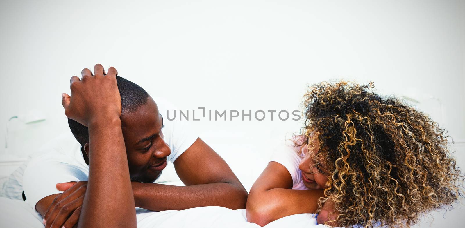 Young couple lying on bed and talking by Wavebreakmedia