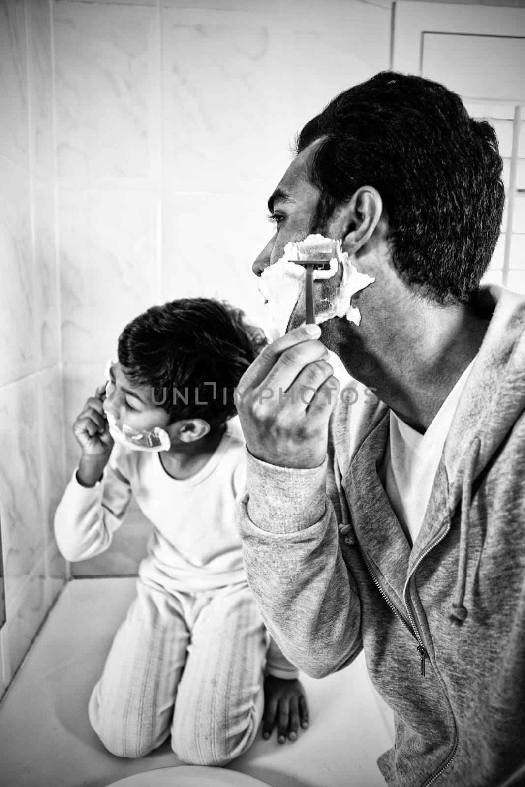 Father and son shaving together in the bathroom at home