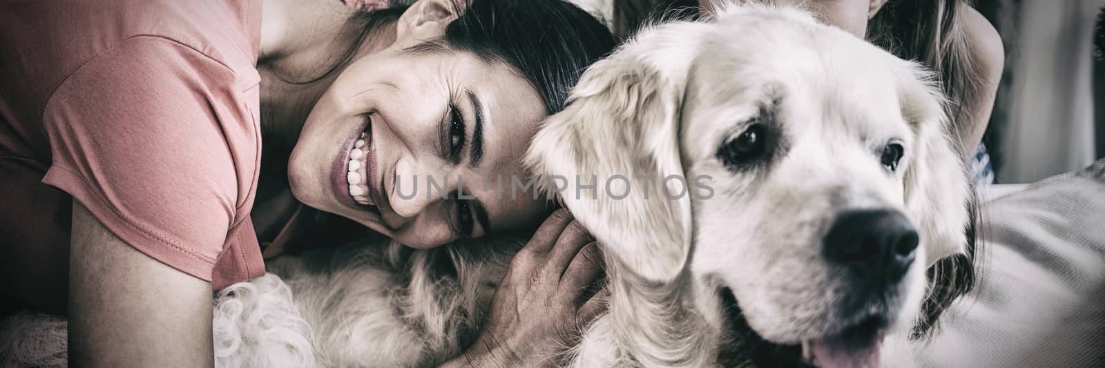 Mother and daughter with dog sitting in living room by Wavebreakmedia