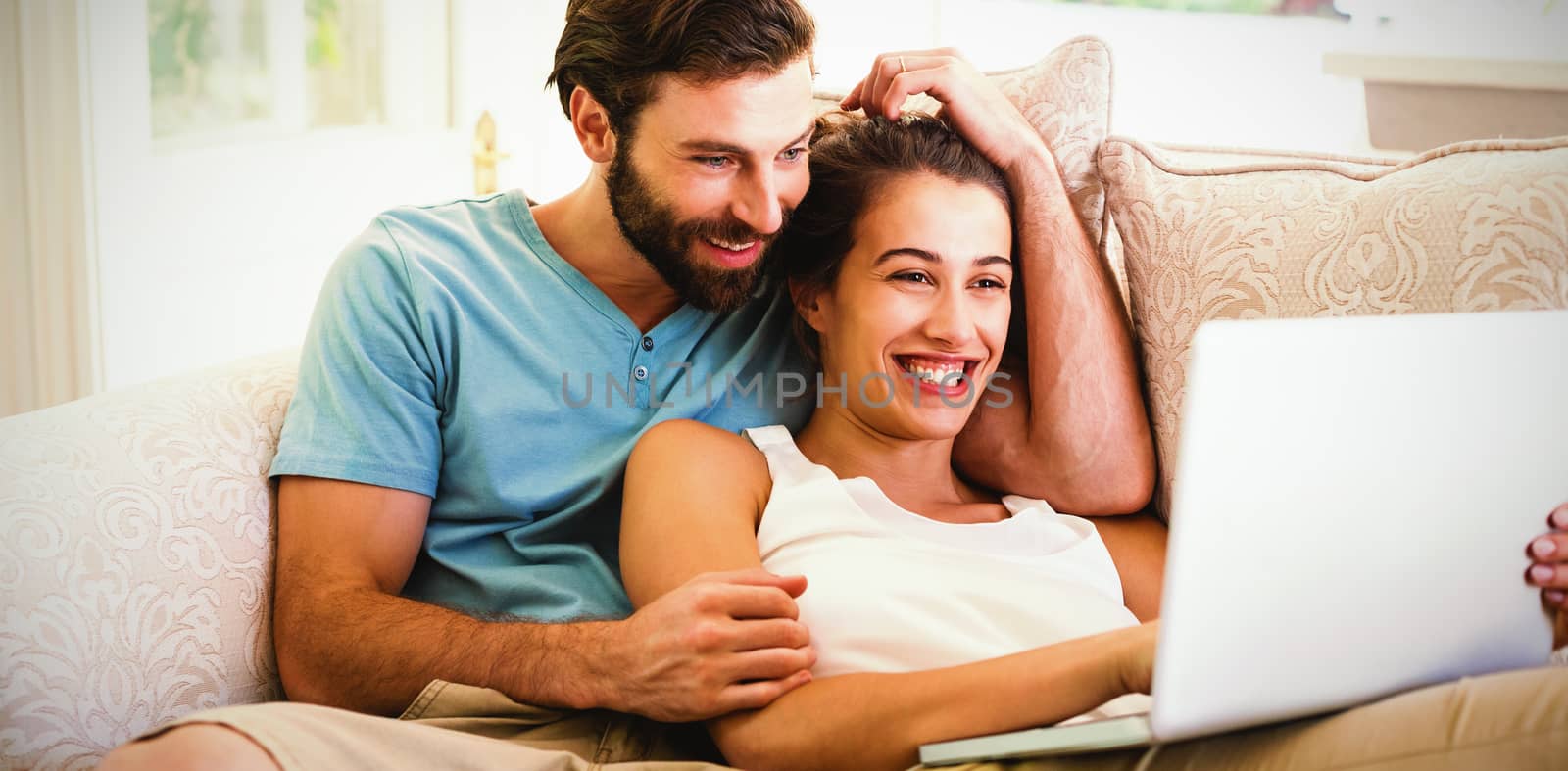 Couple sitting on sofa and using laptop by Wavebreakmedia