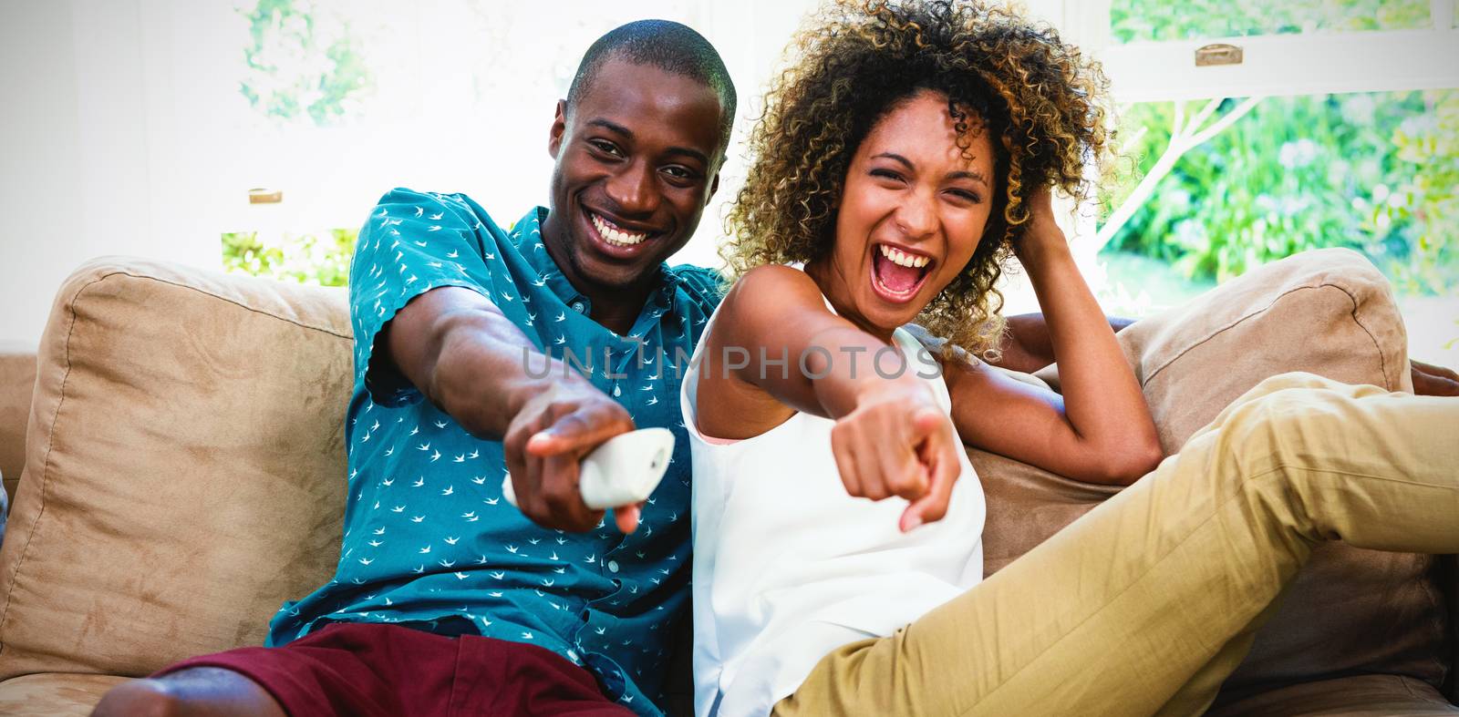 Happy young couple watching television in living room