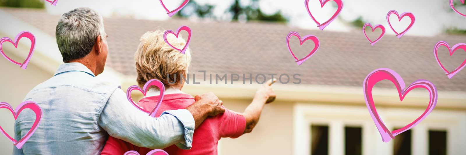 Red Hearts against senior couple looking at house while standing ih yard 