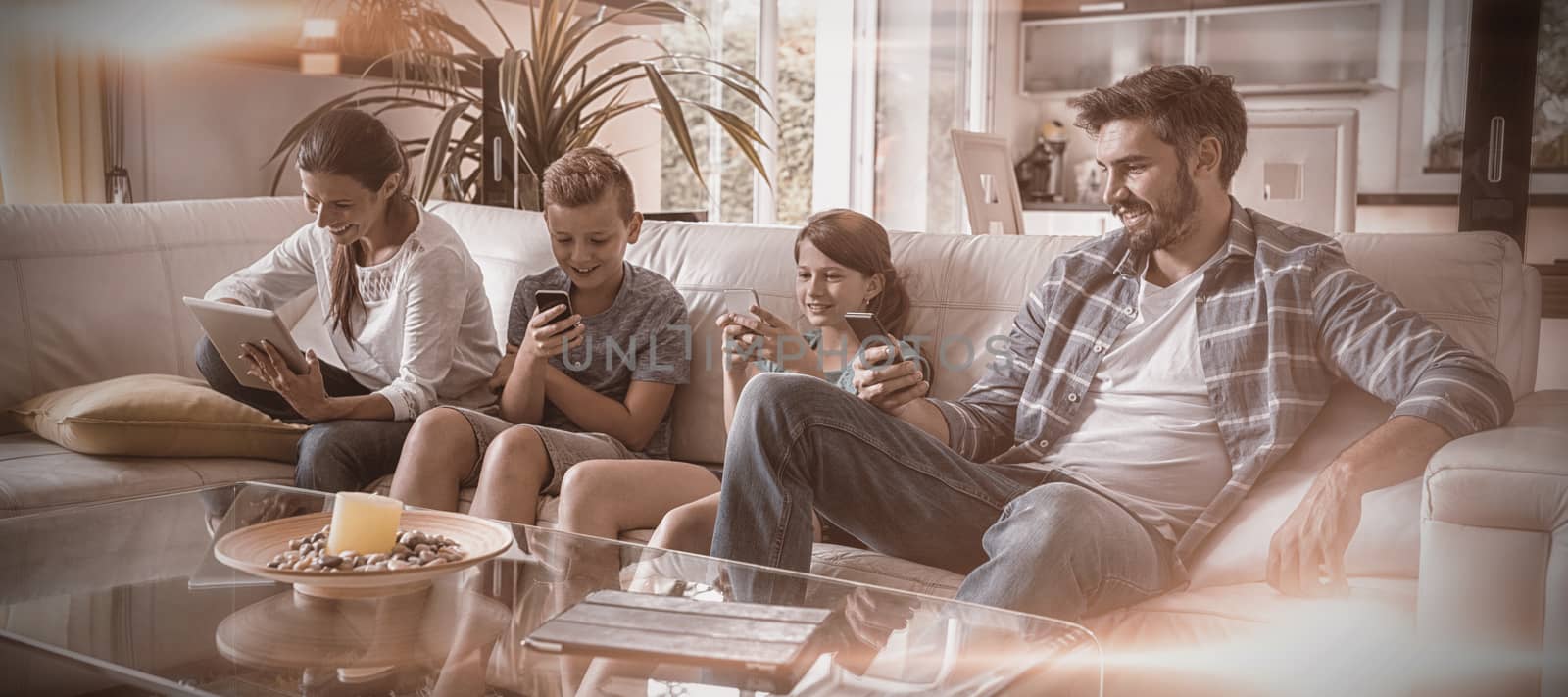 Family using digital tablet and mobile phone in living room by Wavebreakmedia