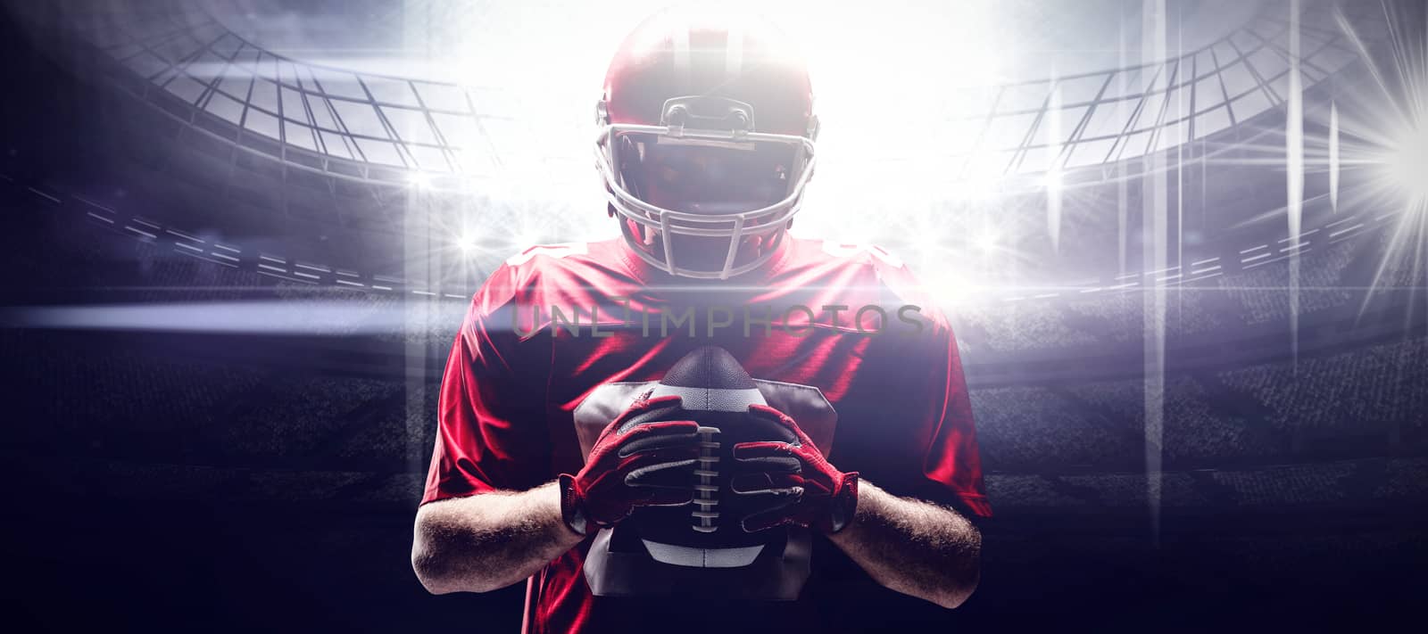 American football player standing with rugby helmet and ball against american football arena