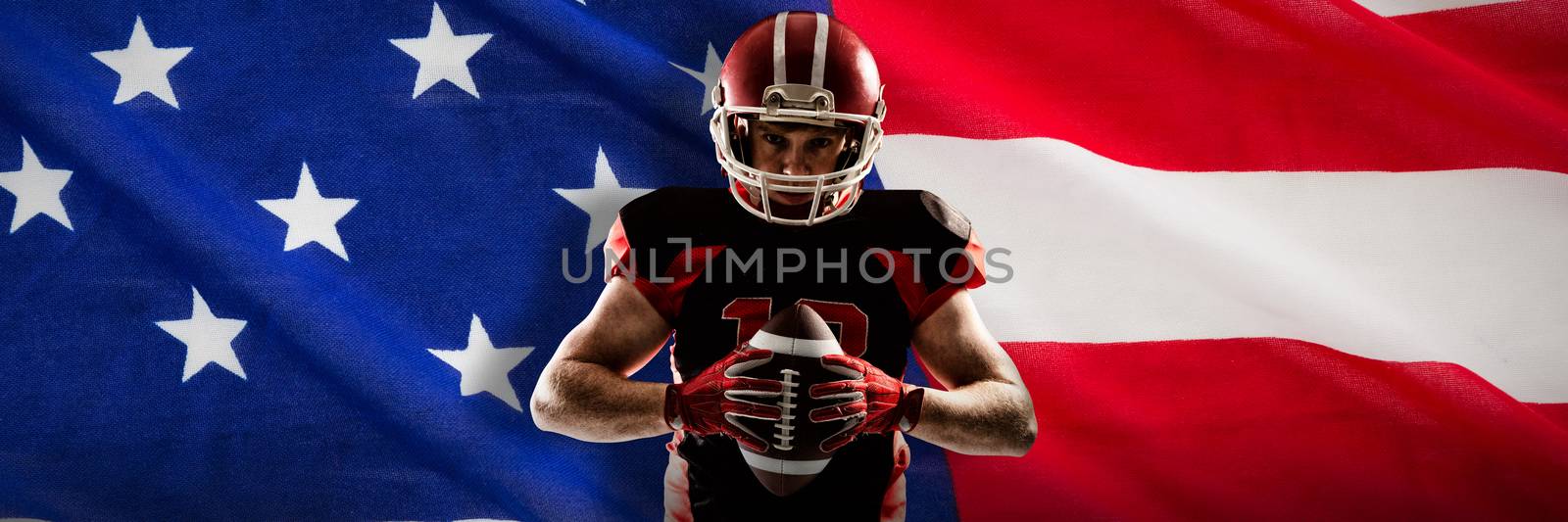 American football player standing with helmet and ball against close-up of an american flag