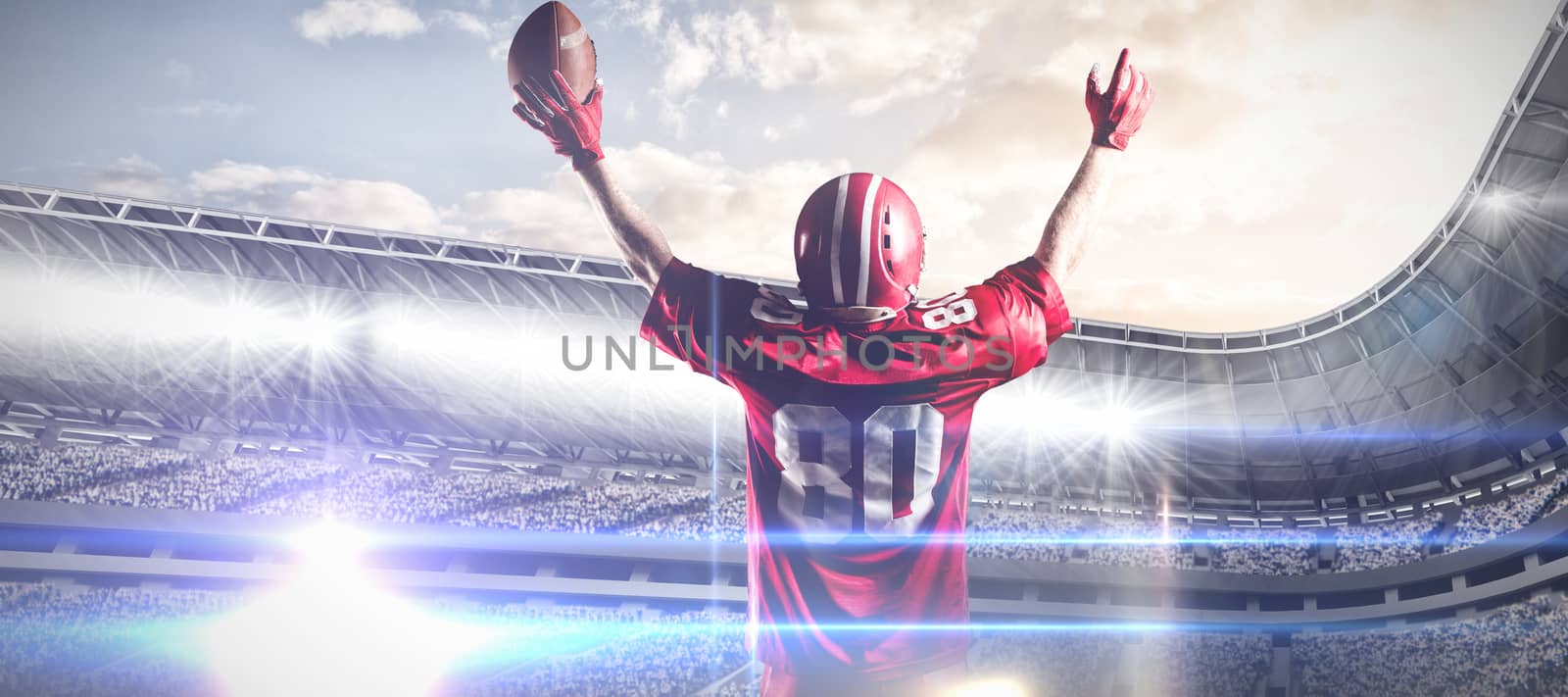 Composite image of american football player in helmet holding rugby ball with arms in the air by Wavebreakmedia