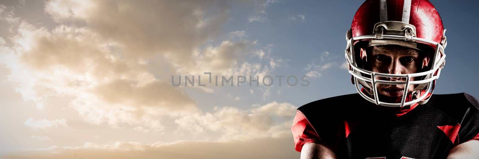 American football player standing in helmet  against cloudy sky landscape