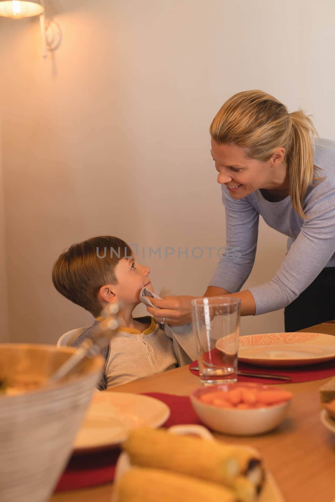 Mother wiping sons mouth with a napkin on dining table by Wavebreakmedia