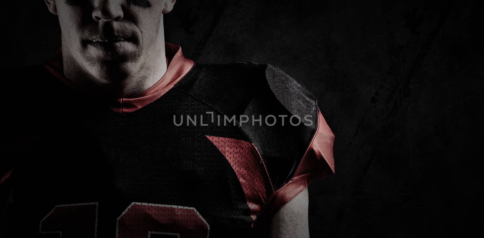 American football player standing against close up of grunged wall