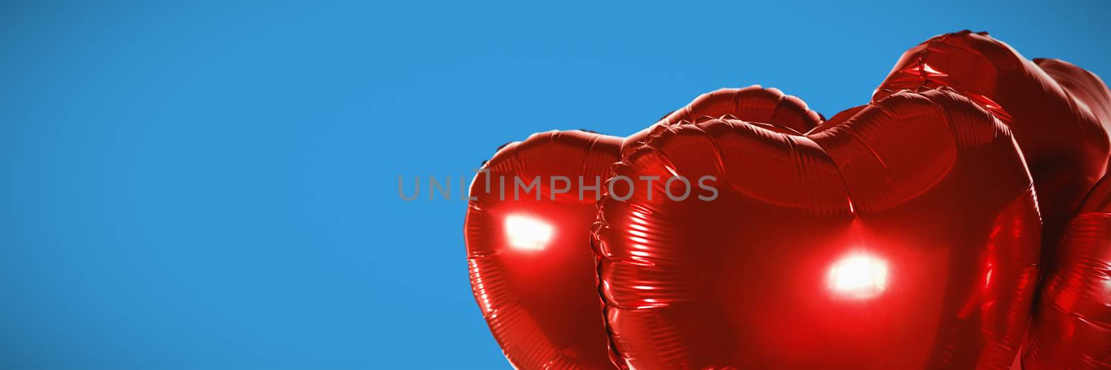 Red heart shape balloons against blue background