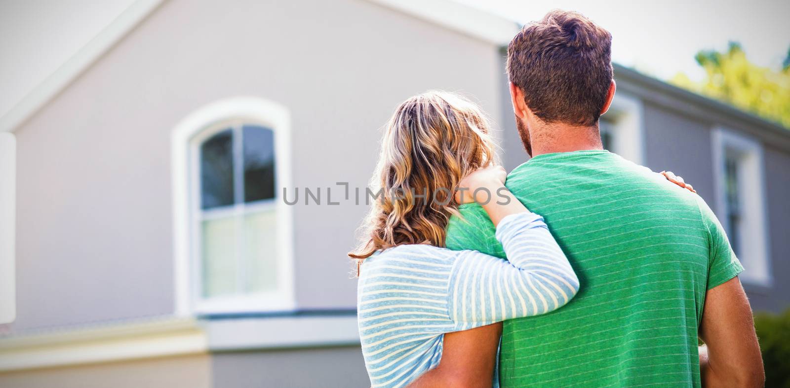 Couple embracing while standing against house