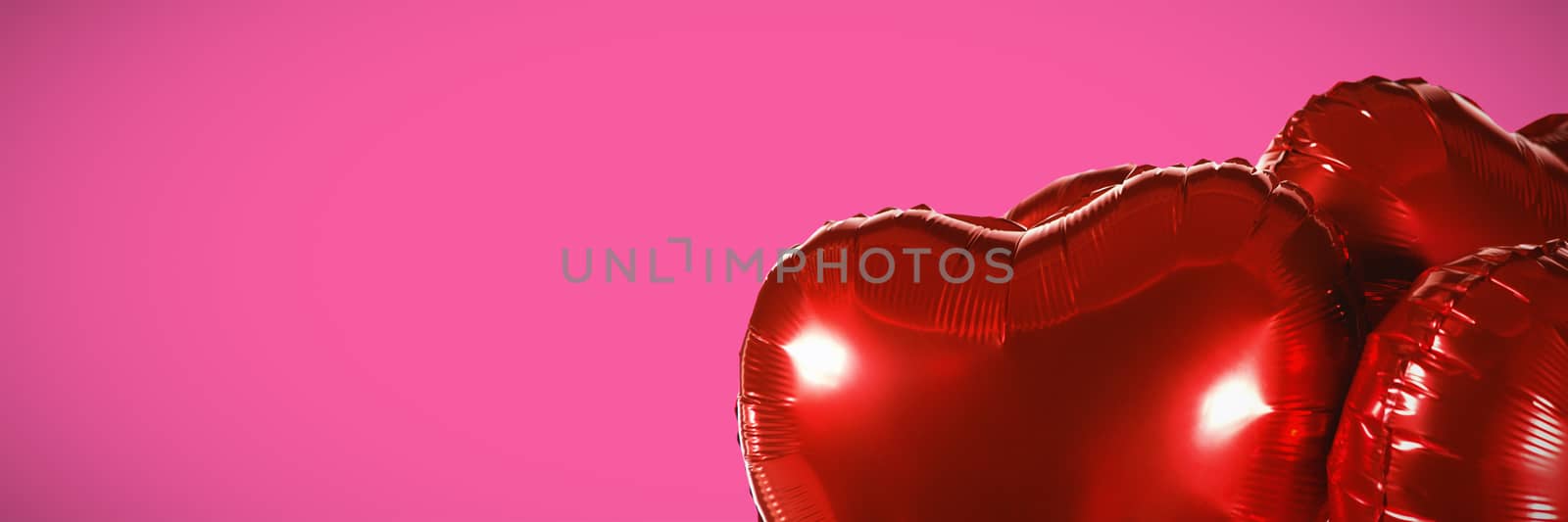 Red heart shape balloons against pink background