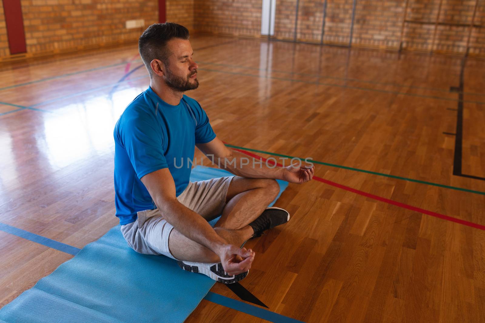 Side view of yoga teacher doing yoga and meditating on a yoga mat in school