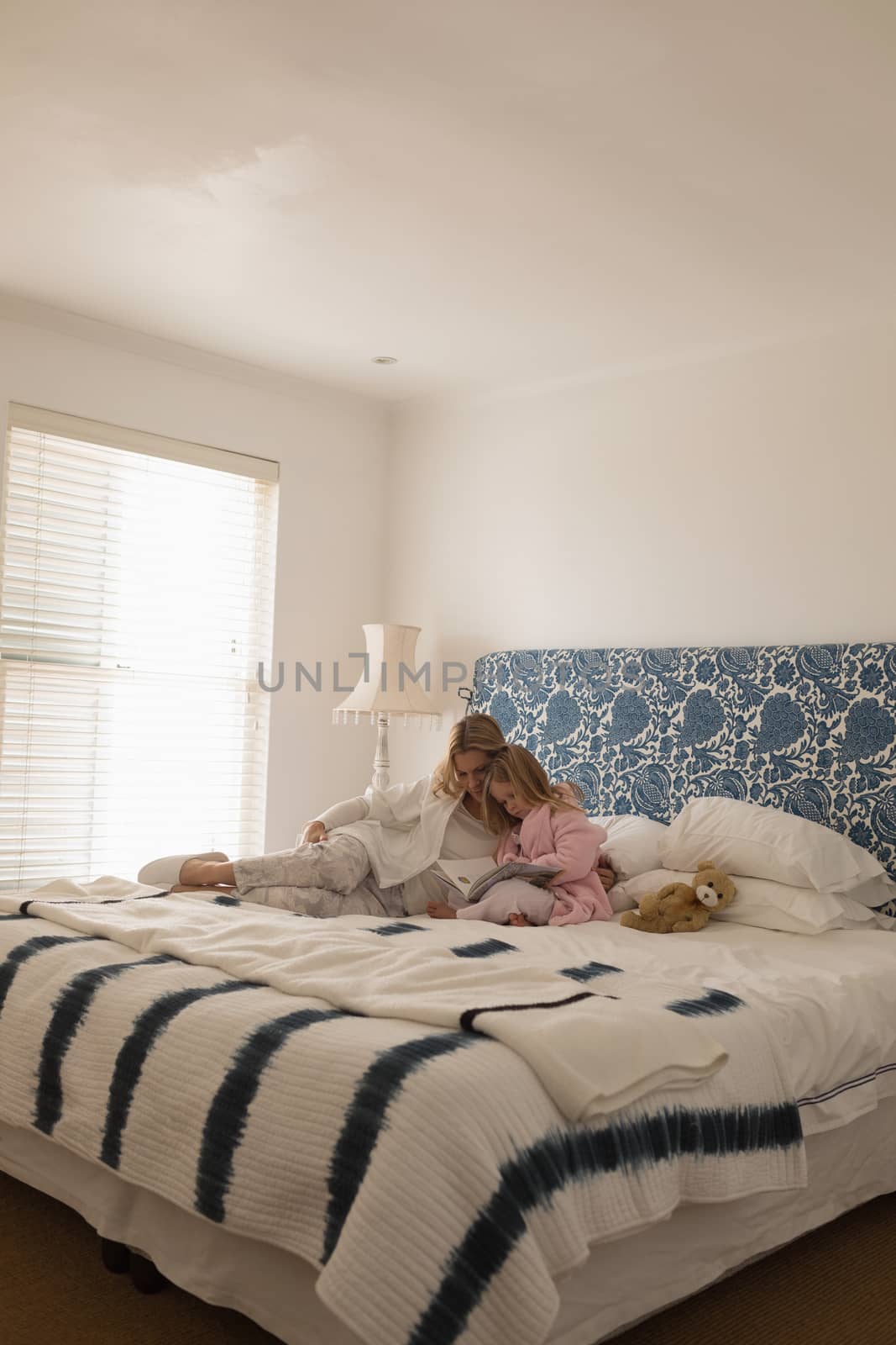 Mother with her daughter reading storybook in bedroom by Wavebreakmedia