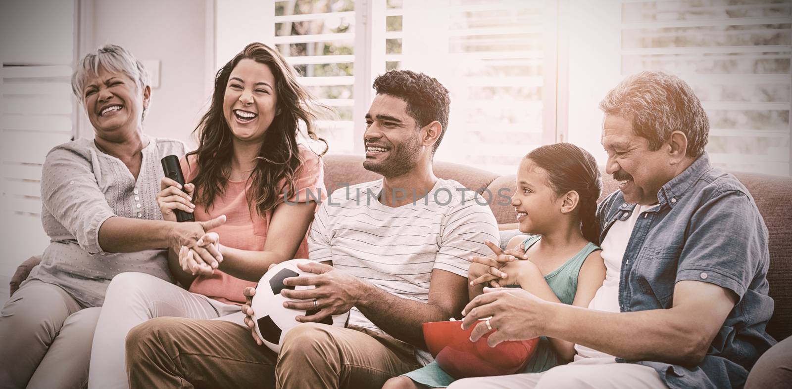 Happy multi-generation family watching soccer match on television in living room by Wavebreakmedia