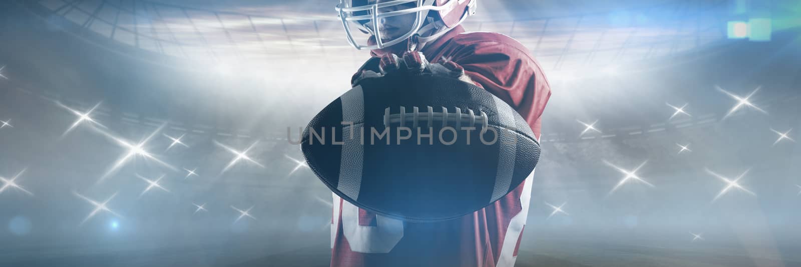 Young American football player standing in rugby helmet and holding rugby ball