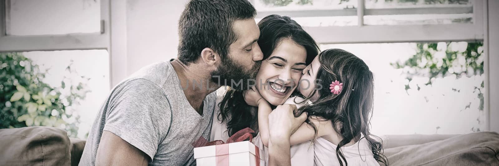 Happy mother receiving gift from her husband and daughter in living room