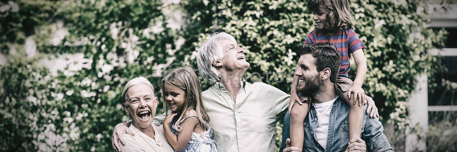 Happy grandparents with grandchildren and son standing in yard 