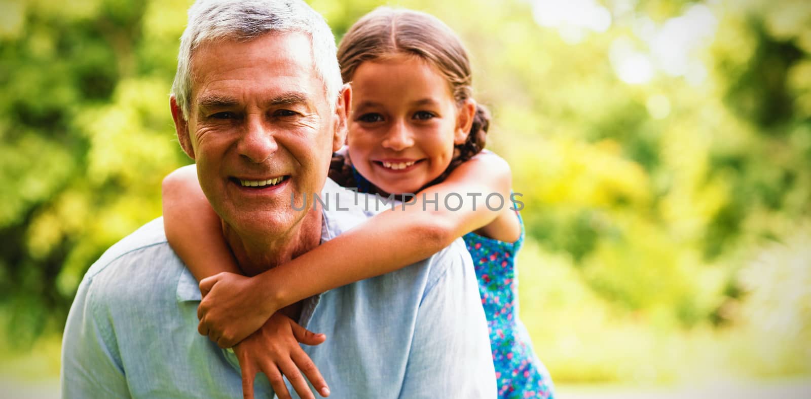 Smiling grandfather carrying grandaughter in yard 