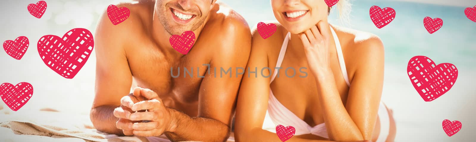 Red Hearts against young couple lying on beach