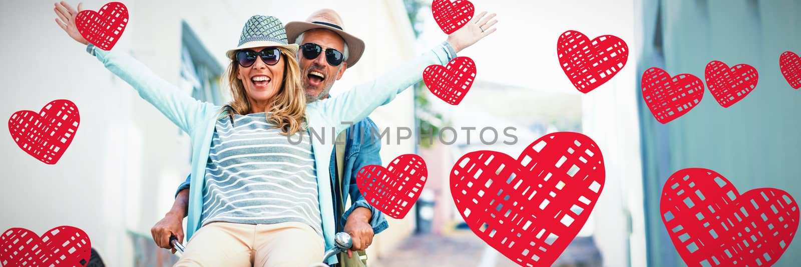 Red Hearts against happy couple enjoying while riding bicycle