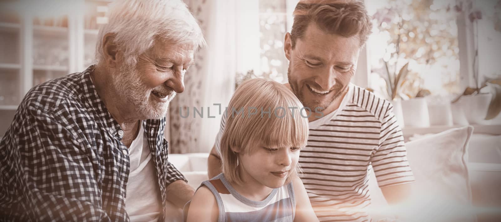Boy using digital tablet with his father and grandfather in living room by Wavebreakmedia