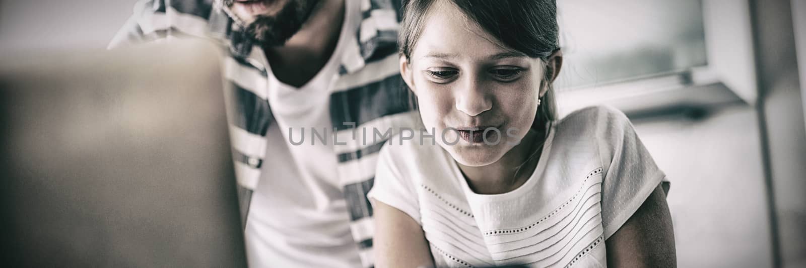 Father and daughter using laptop and mobile phone in the living room at home