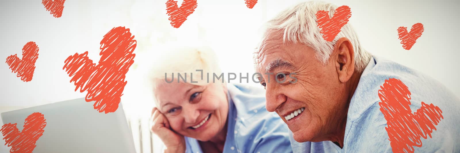 Red Hearts against senior couple using laptop in bedroom