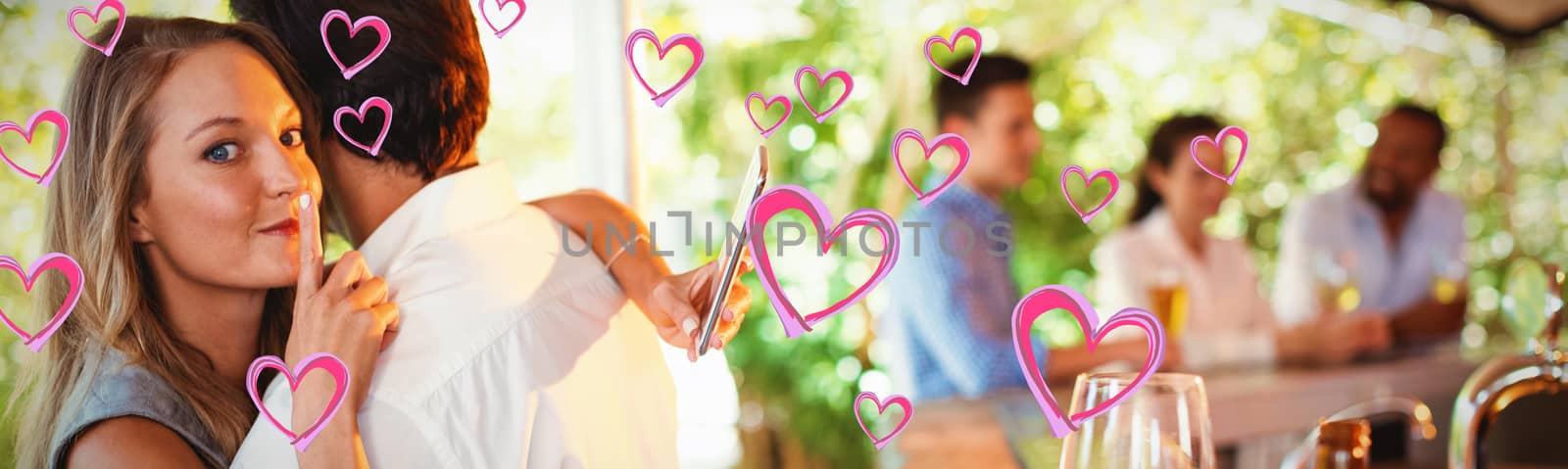 Red Hearts against couple embracing while using mobile phone