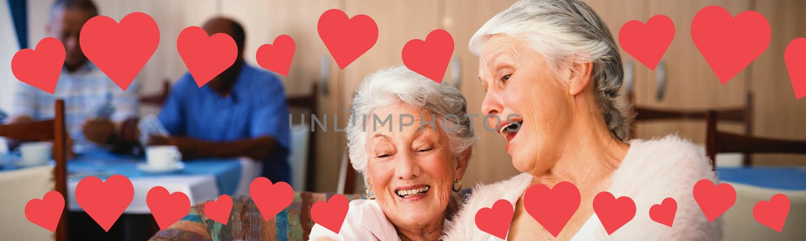 Graphic image of heart shapes against senior friends taking selfie through smart phone