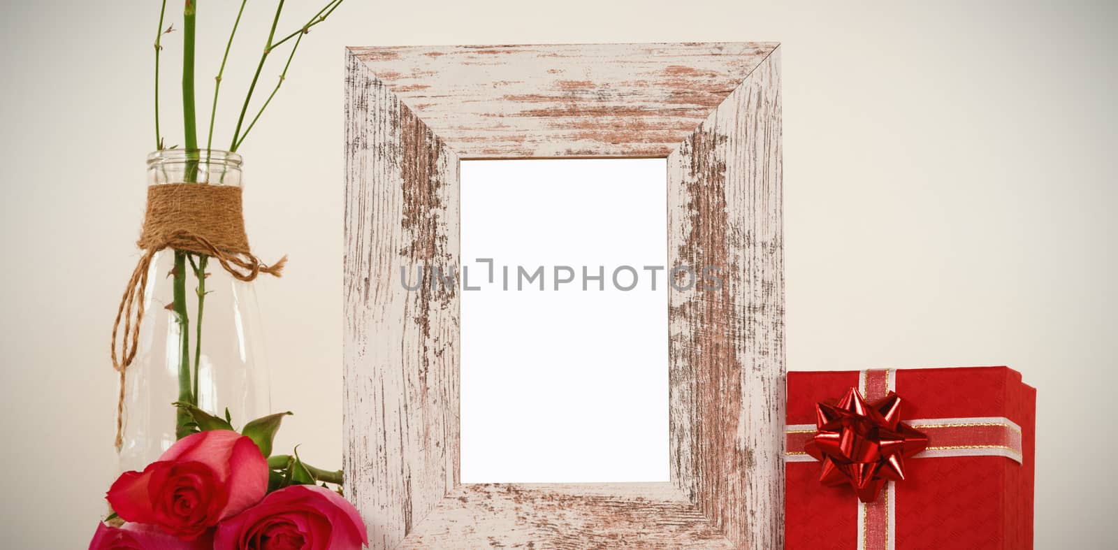 Rose flower in glass vase, empty photo frame and gift box