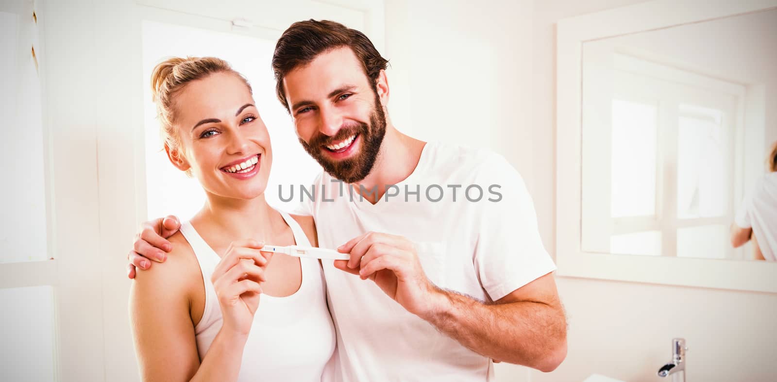 Portrait of happy couple checking pregnancy test in bathroom