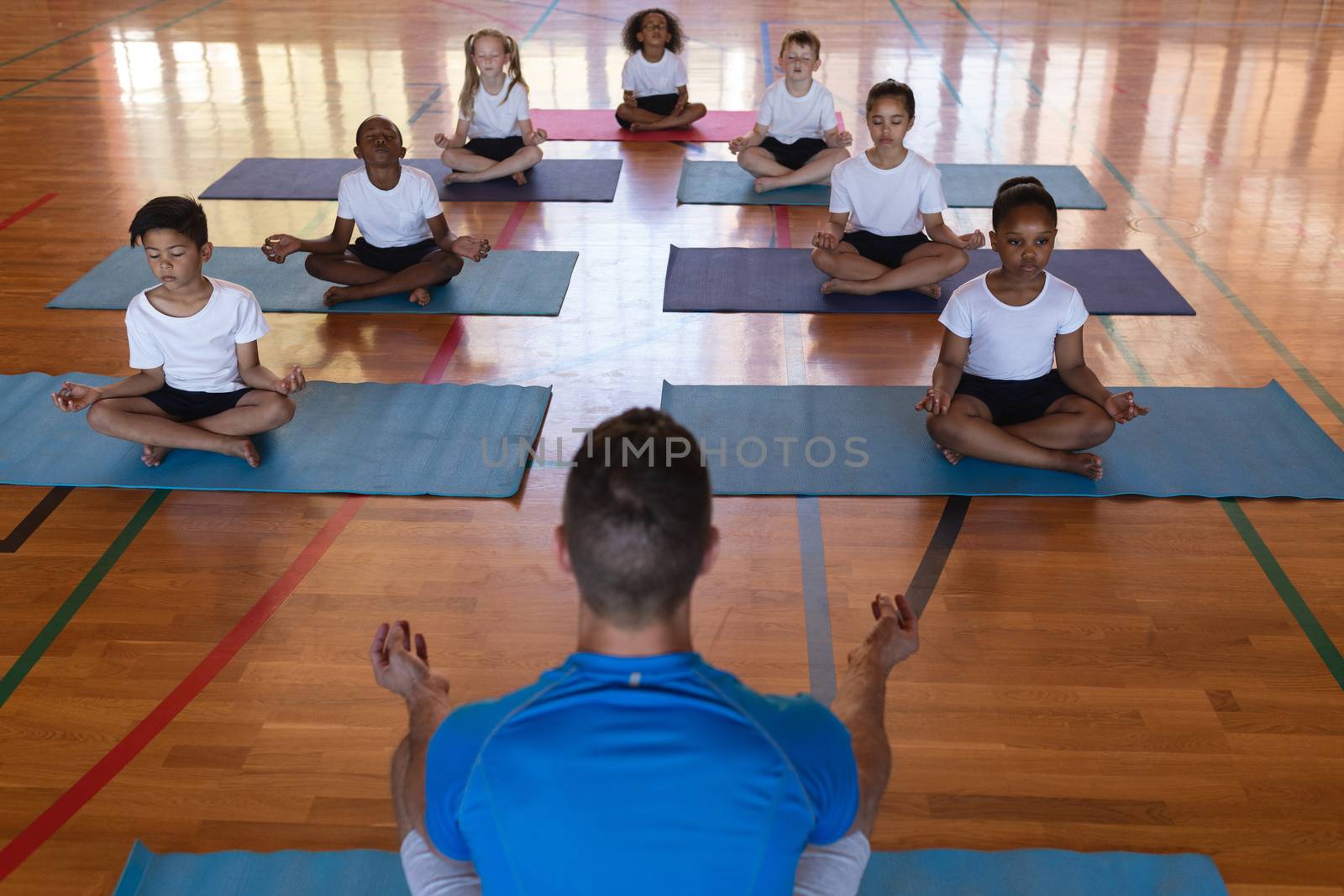 Yoga teacher teaching yoga to school kids in school by Wavebreakmedia