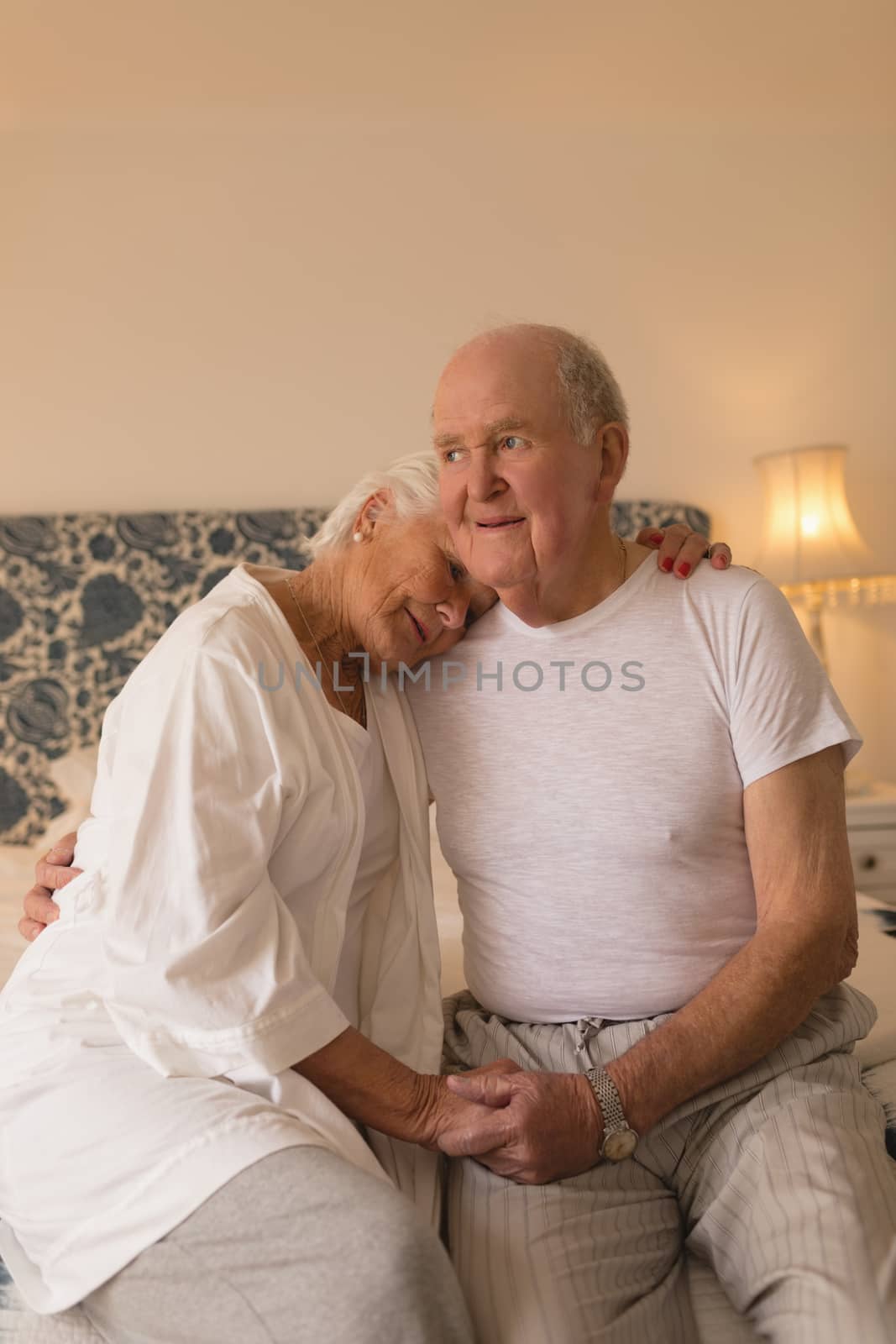 Front view of happy senior couple embracing each other relaxing in bedroom at home