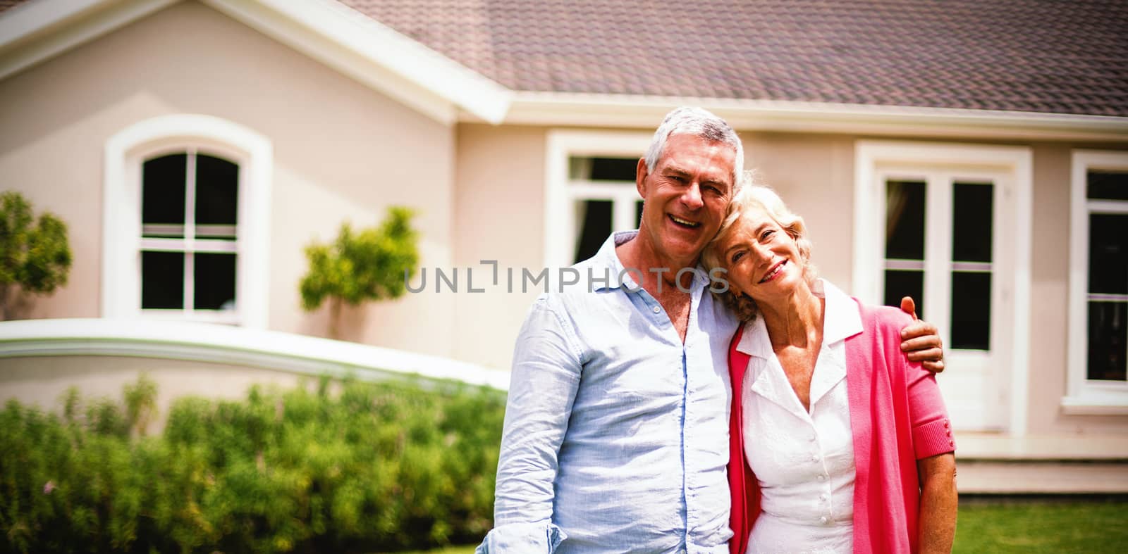 Senior couple with arms around standing in yard  by Wavebreakmedia
