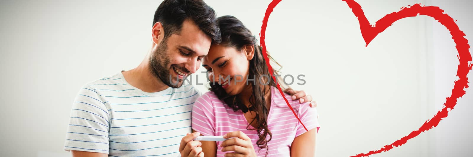 Heart against joyful couple finding out results of a pregnancy test in the bedroom