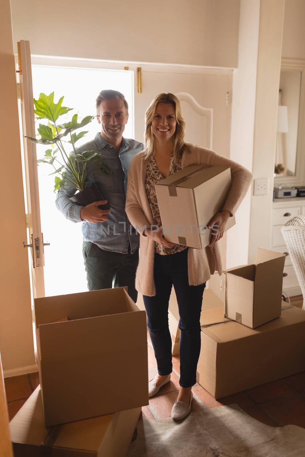 Portrait of attractive happy couple wearing casual clothes moving into new home