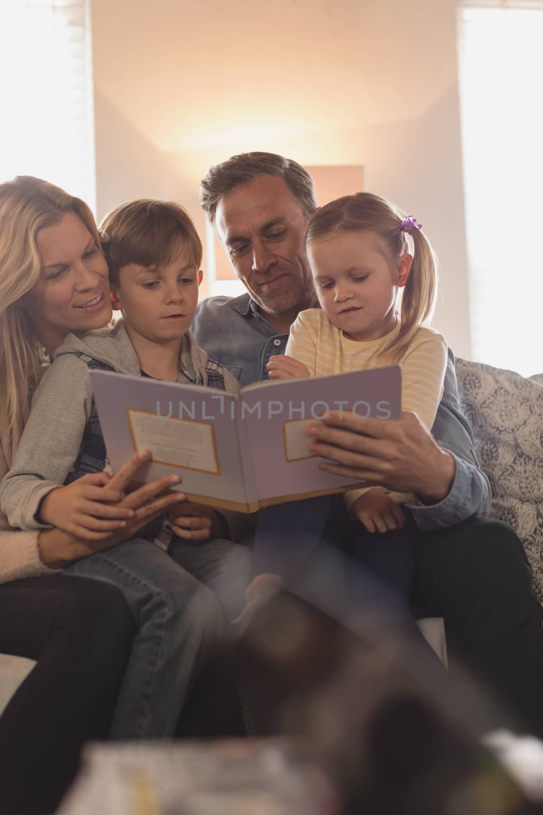 Family reading story book in living room by Wavebreakmedia