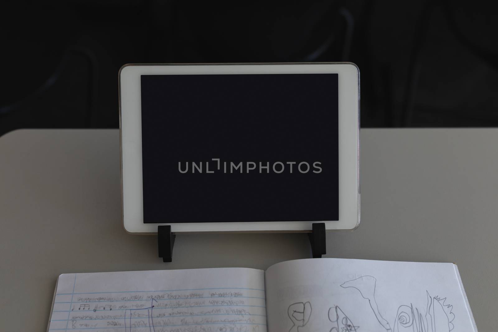 Close-up of digital tablet and notebook with notebook on desk in classroom
