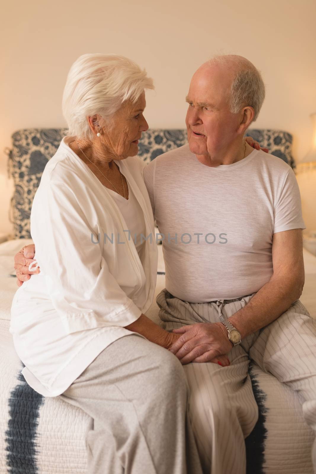 Front view of senior couple looking at each other on bed in the bedroom at home