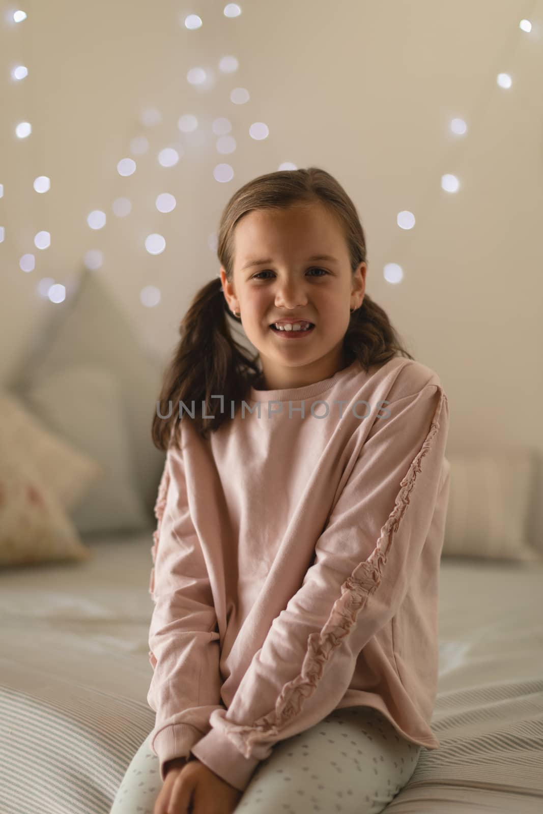 Portrait of innocent girl sitting in bedroom at home