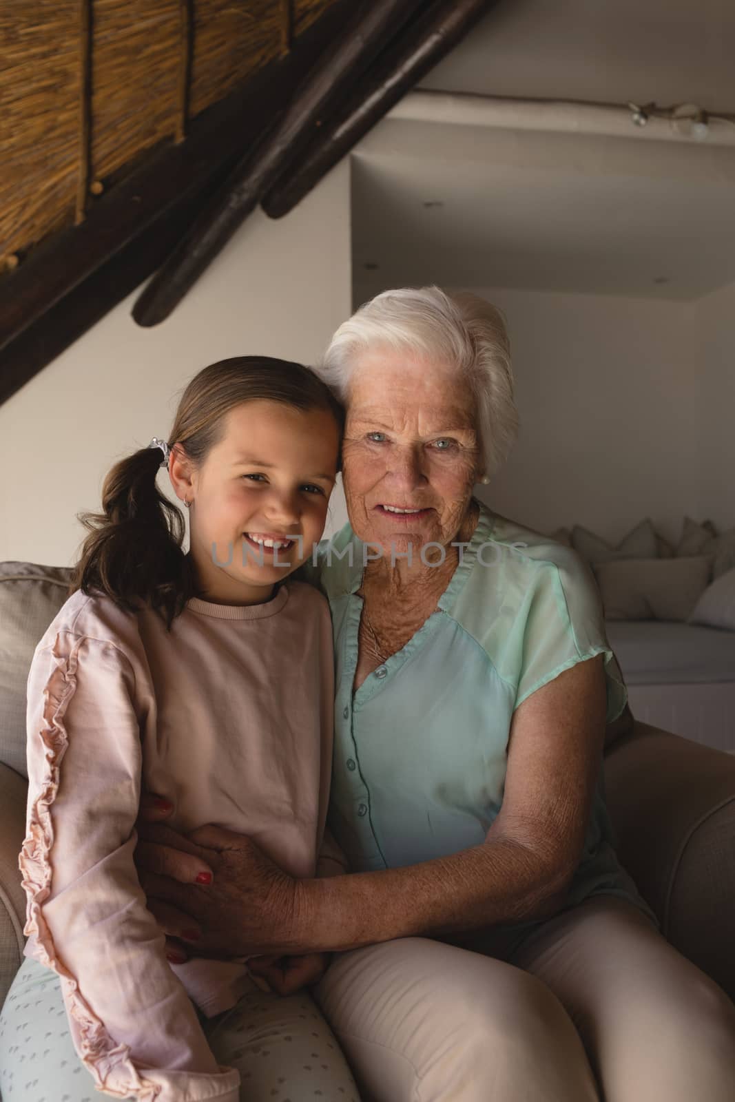 Portrait of grandmother and granddaughter relaxing together in living room at home